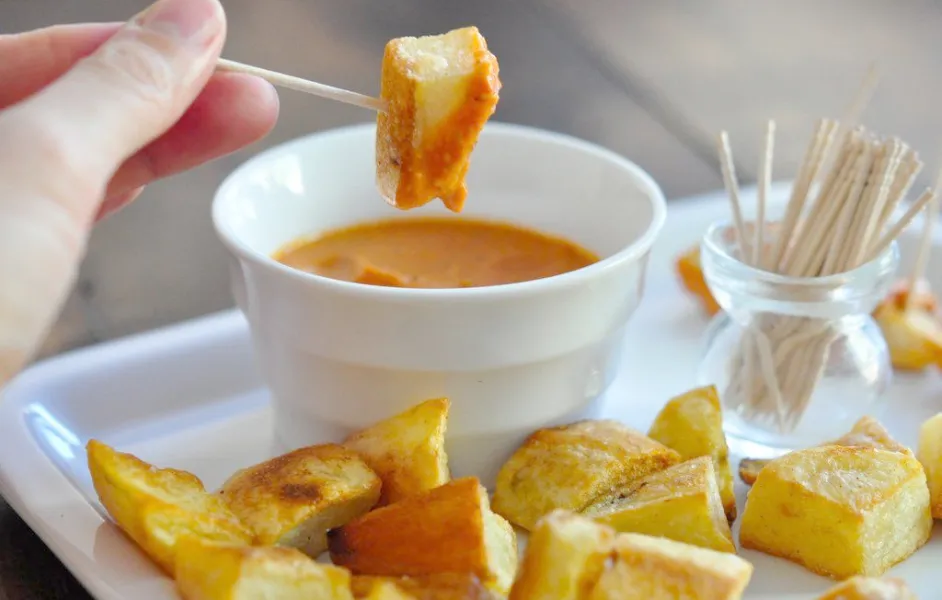 A small glass of vermouth and a plate of patatas bravas- tapas