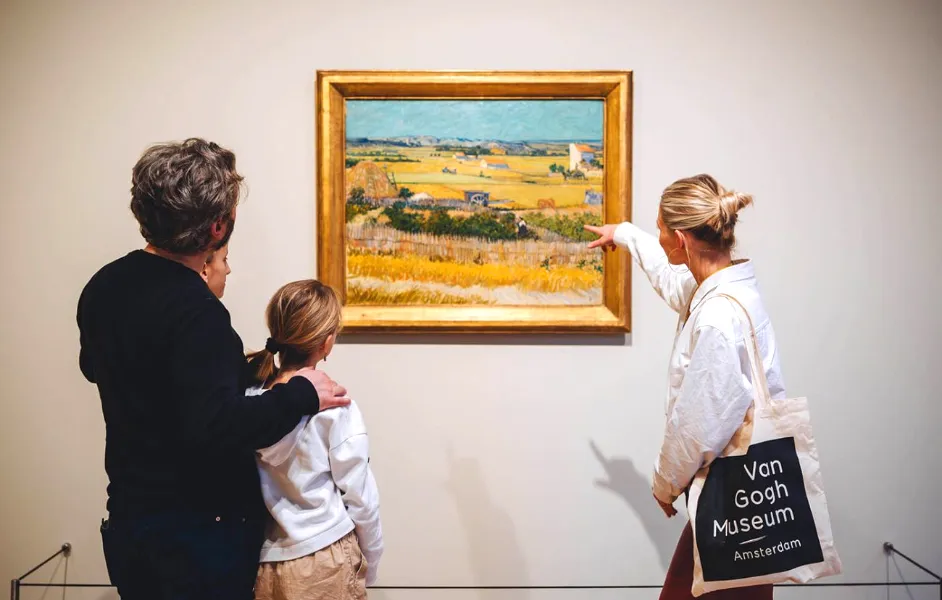 a small group with a guide pointing at a painting